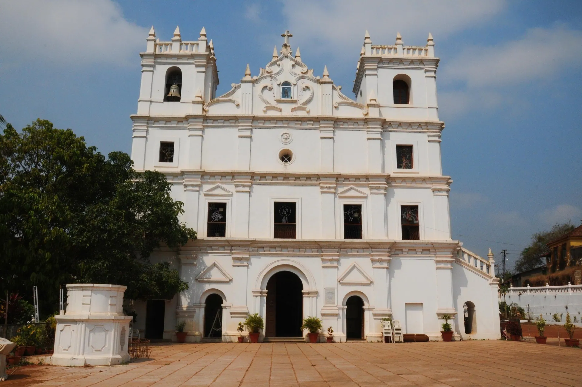 The whitewashed twin-towered facade of St Thomas Church, Aldona, with its paved forecourt, North Goa