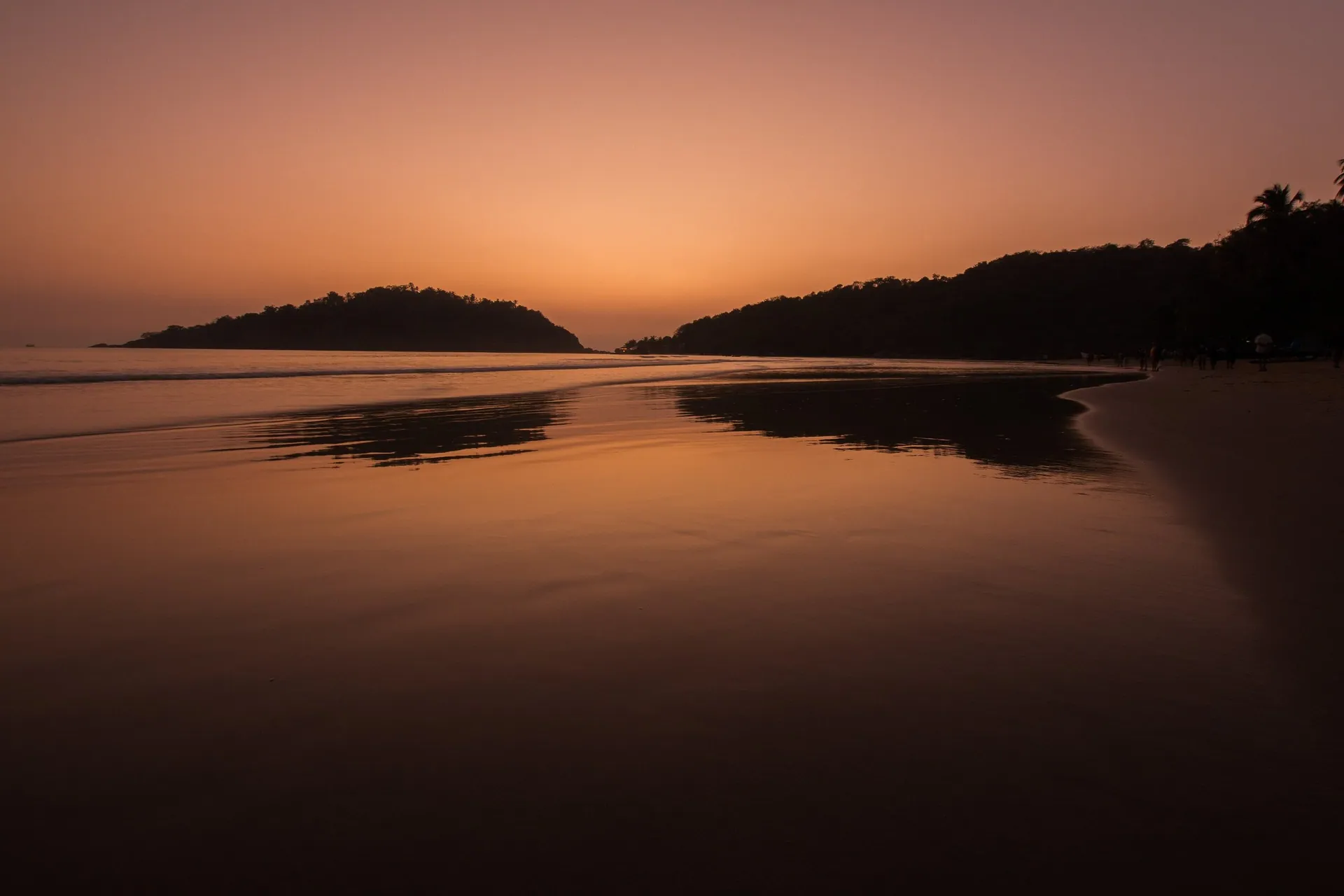Sunset over Palolem beach in South Goa, with the headland in silhouette